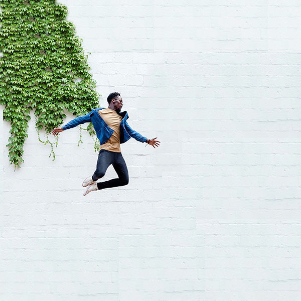Man jumping in front of a brick, ivy-covered wall at The Lurgan. Washington, DC . Photoshoot by Gold Dog Communications.